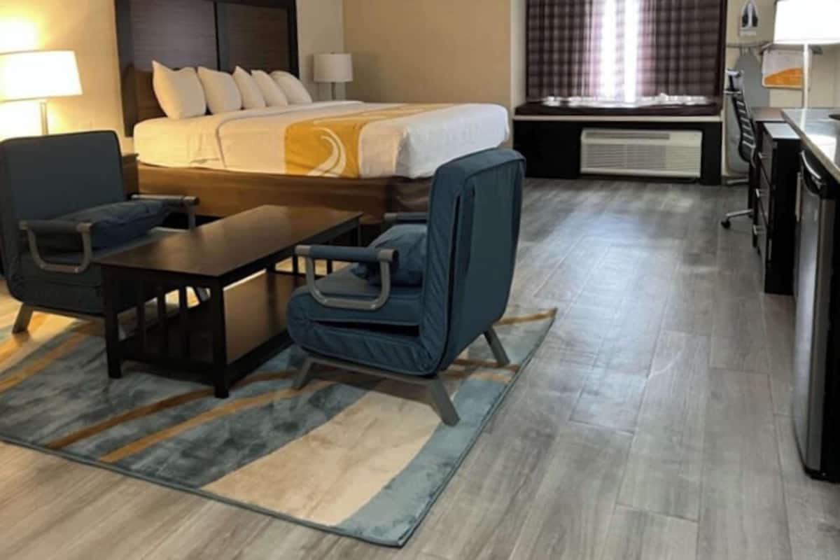 A hotel room with a bed, desk, chair, and a small table.