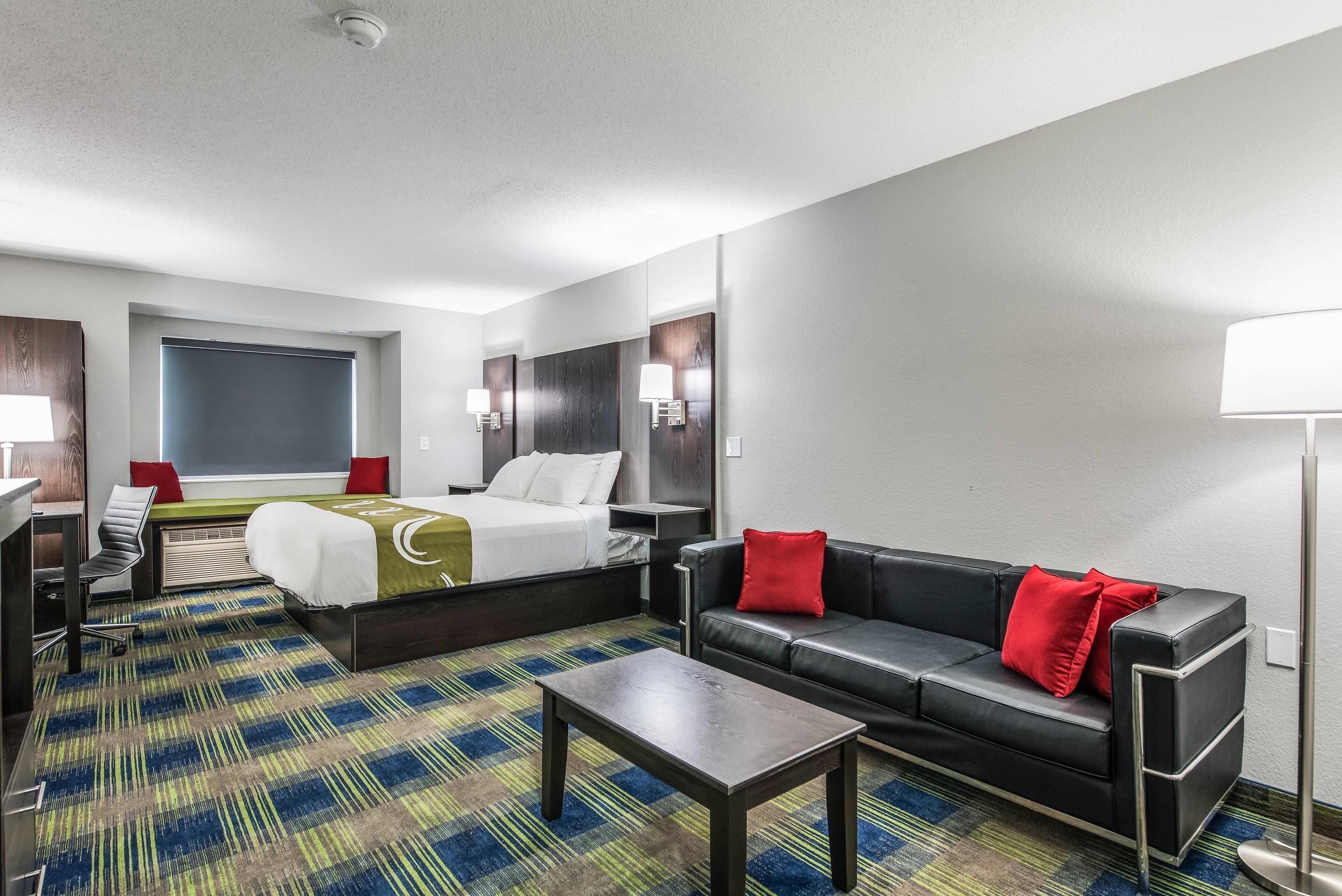 Una habitación de hotel con cama, sofá, escritorio y lámpara.