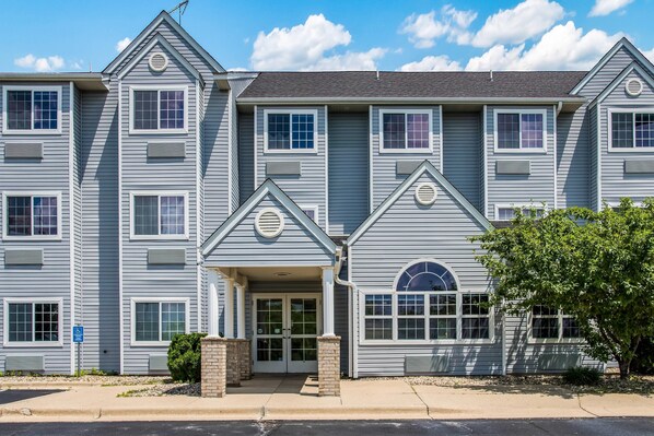 A multi-story residential building with a symmetrical facade, multiple windows, and a central entrance with a door and a small porch.