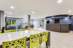 Ein moderner Essbereich mit einem langen Tisch, grünen Stühlen mit runden Aussparungen und einer blauen Akzentwand.