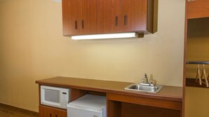 A compact kitchenette with a microwave, a small refrigerator, and a sink.