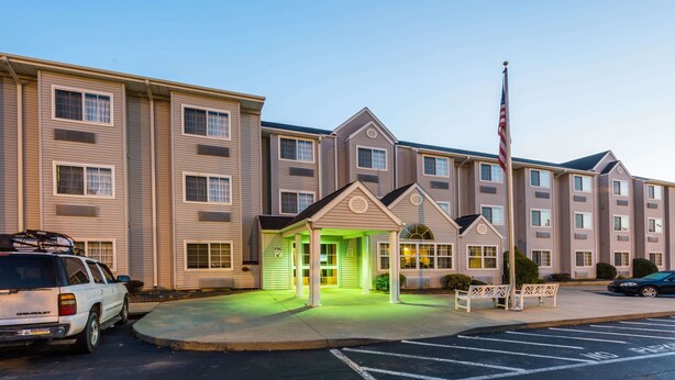 A multi-story hotel with a covered entrance, a flagpole, and a parking area.