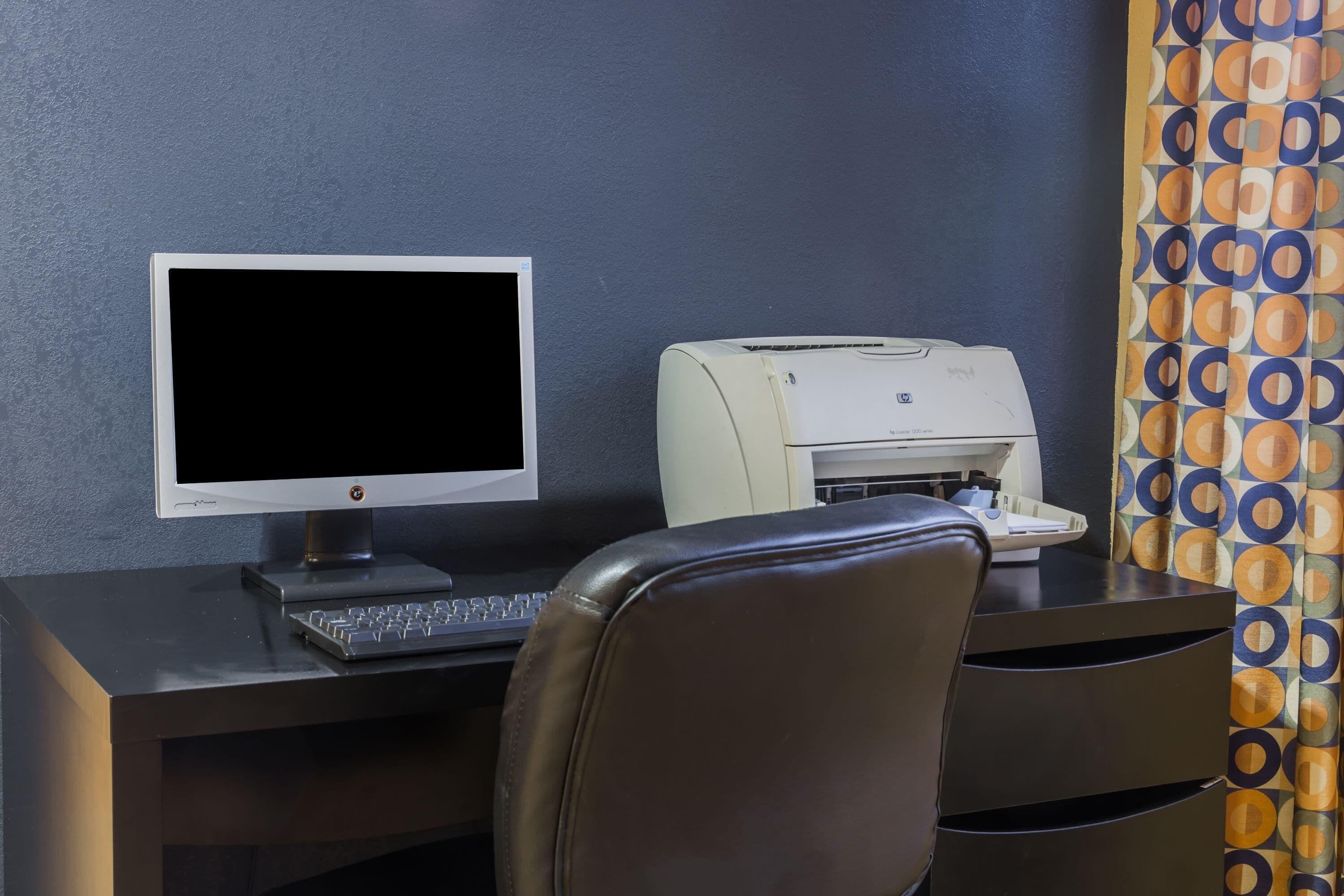 Un escritorio con monitor de computadora, teclado e impresora.