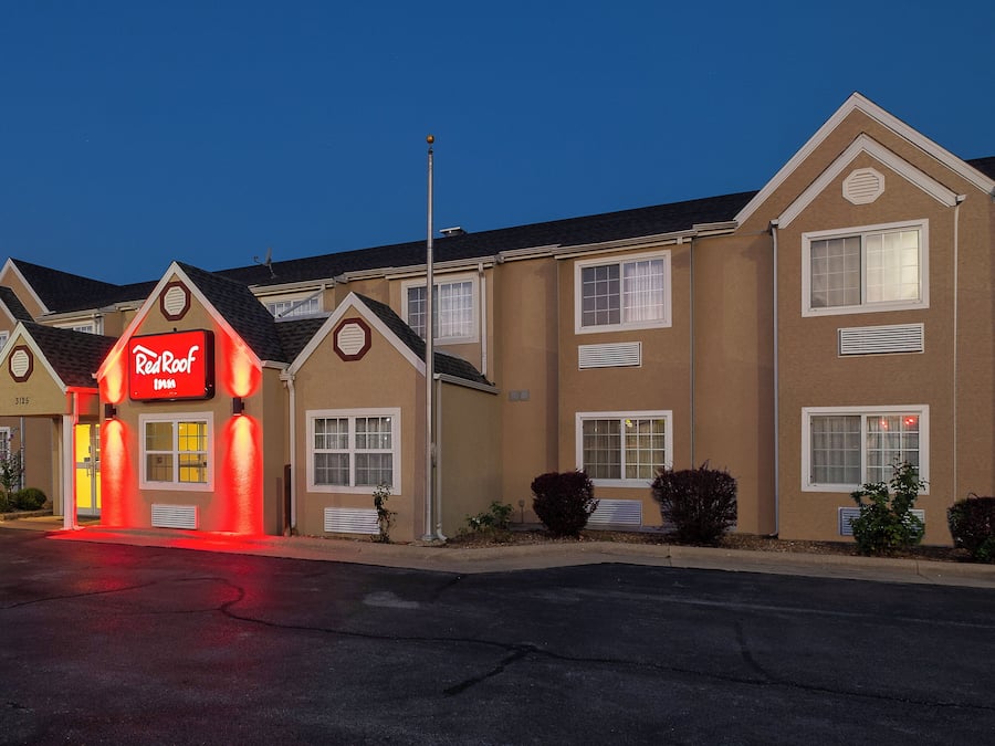 A Red Roof Inn with a traditional architectural style, featuring multiple windows and a well-lit entrance.