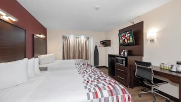 Habitación de hotel con una cama grande, un escritorio con computadora y un televisor de pantalla plana, cafetera y una kitchenette pequeña.