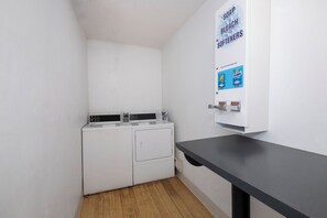 A laundry room with two white washing machines and a black countertop. - Red Roof Inn Springfield, MO (Springfield)