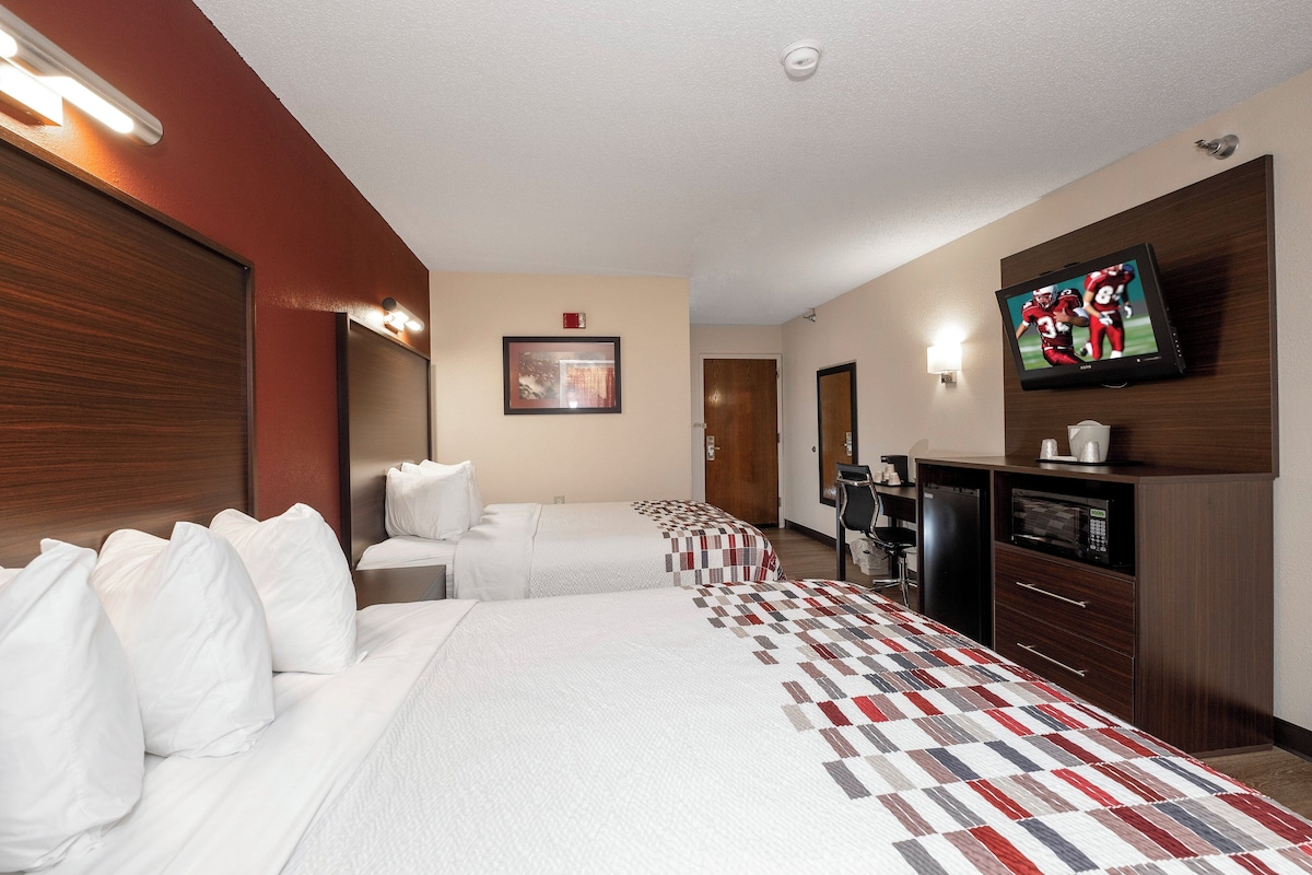 A hotel room with two beds, a TV, a coffee machine, and a microwave.