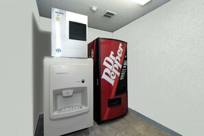 Ein Getränkeautomat und ein kleiner Kühlschrank in einer Ecke.