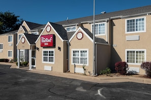 A Red Roof Inn with a modern design, featuring a prominent red and white sign, multiple windows, and a well-maintained exterior.