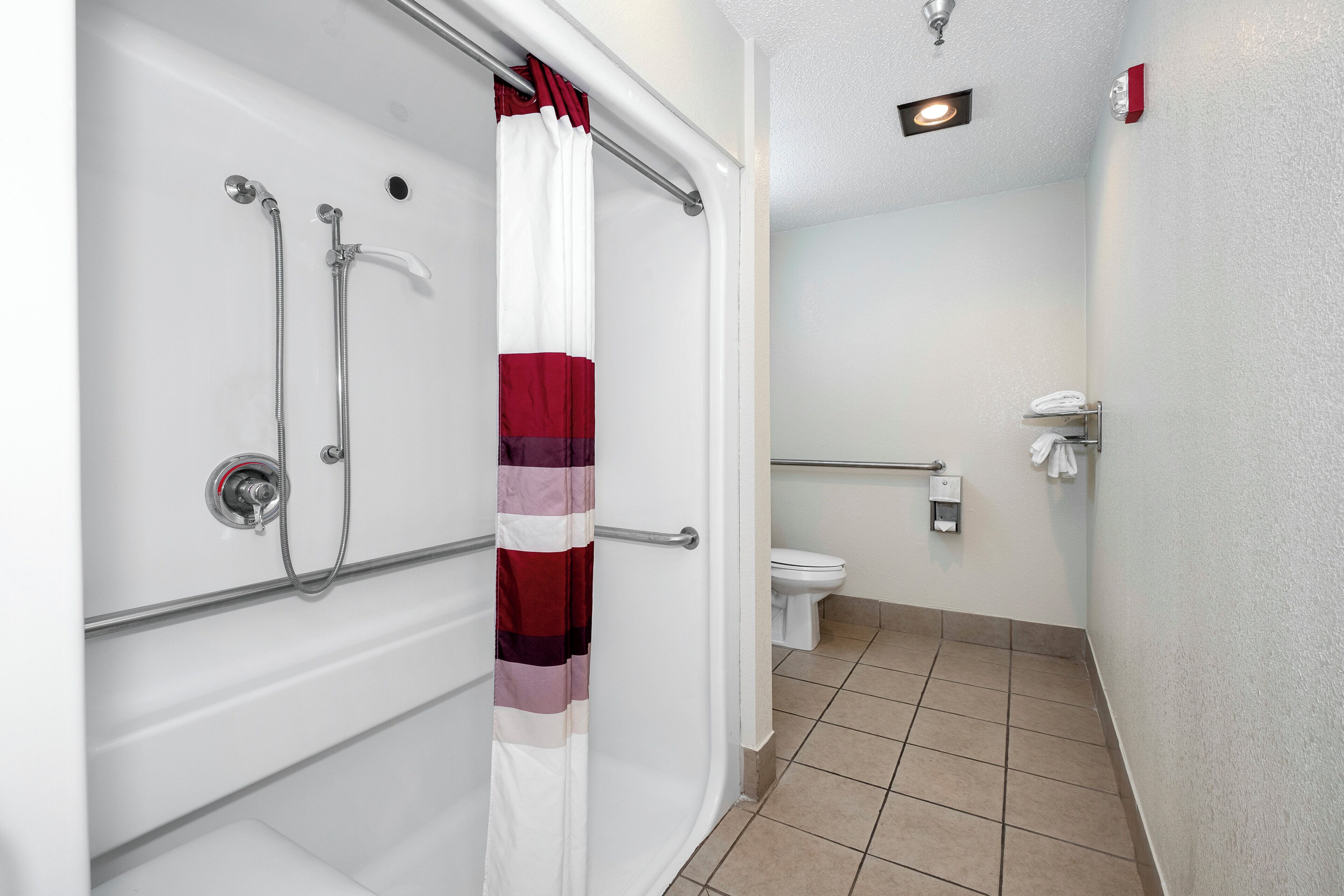 Un baño con ducha, inodoro y secamanos.