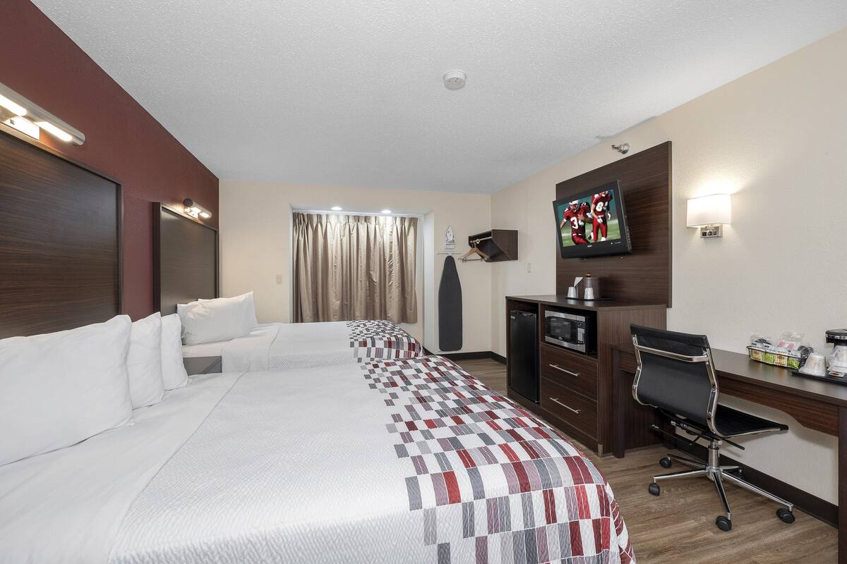 A hotel room with a large bed, a desk with a chair, a television, and a coffee machine.