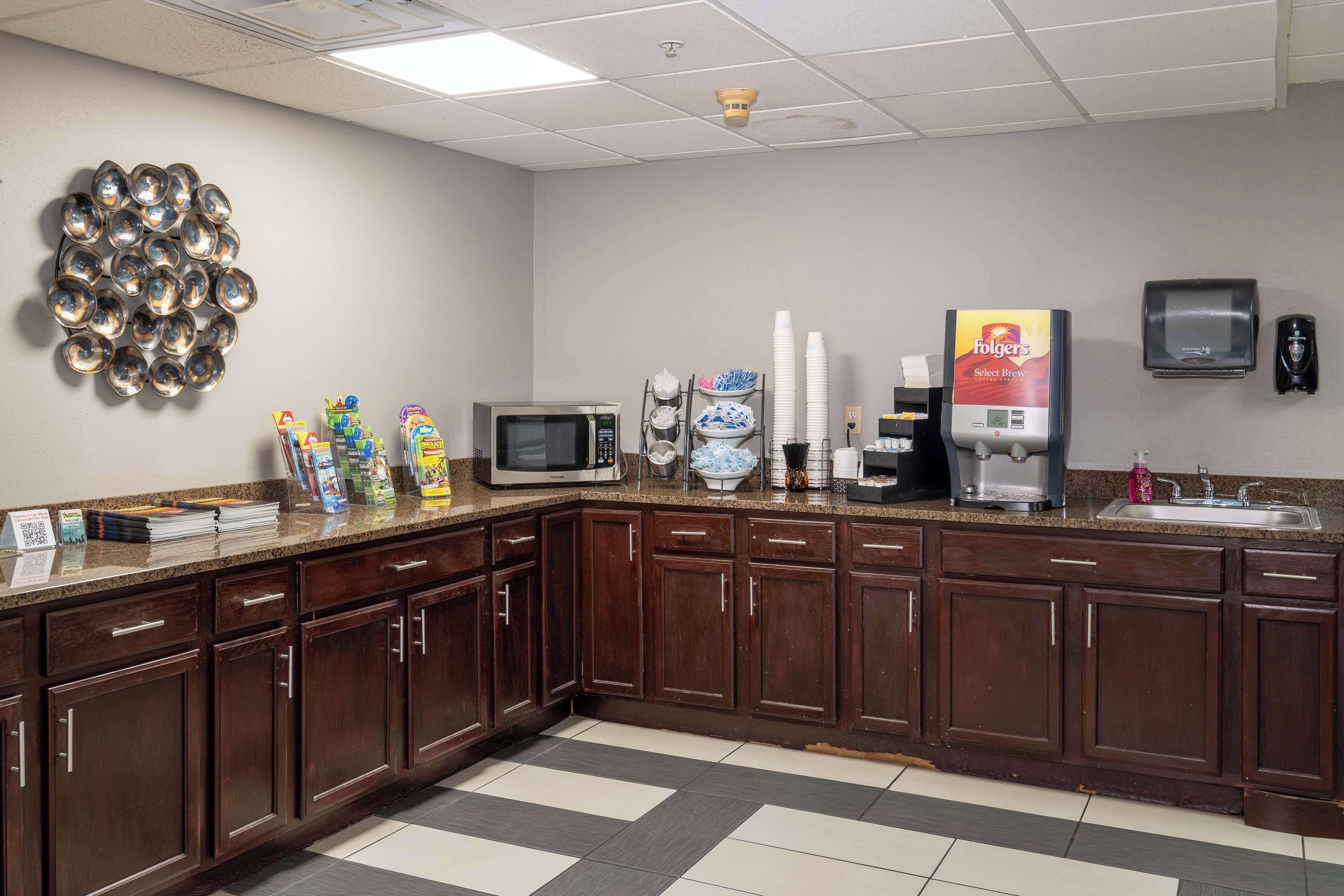 A kitchen area with a microwave, coffee maker, and paper towel dispenser.