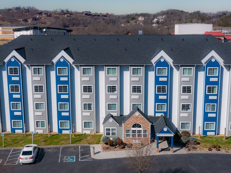 Un hotel a più piani con ingresso centrale e parcheggio.
