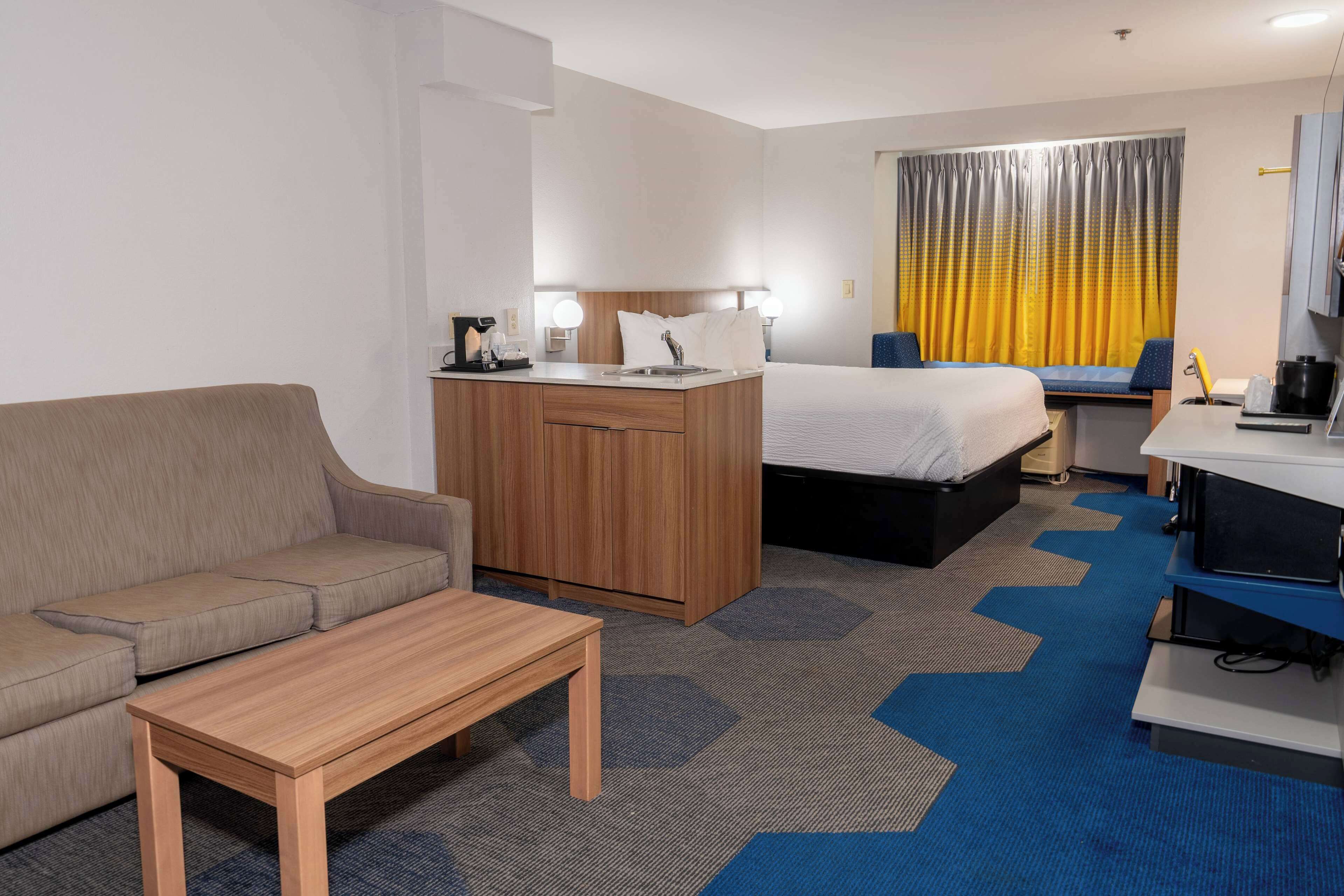 Une chambre d’hôtel équipée d’un canapé, d’un bureau, d’un lit et d’une petite kitchenette.