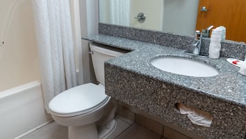 A bathroom with a white toilet, granite countertop sink, and a mirror above the sink.