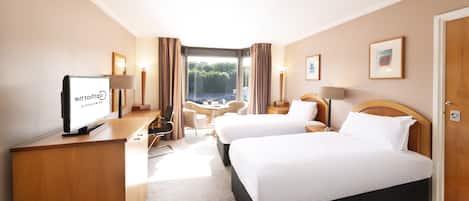 A hotel room with a bed, desk, chair, and a TV displaying 'Gdiplove'.