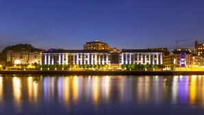 A waterfront hotel with a modern facade, a prominent glass structure, and a reflection in the water. - Copthorne Hotel Newcastle (Newcastle-upon-Tyne)