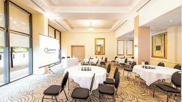 A conference room with round tables, chairs, and a whiteboard.