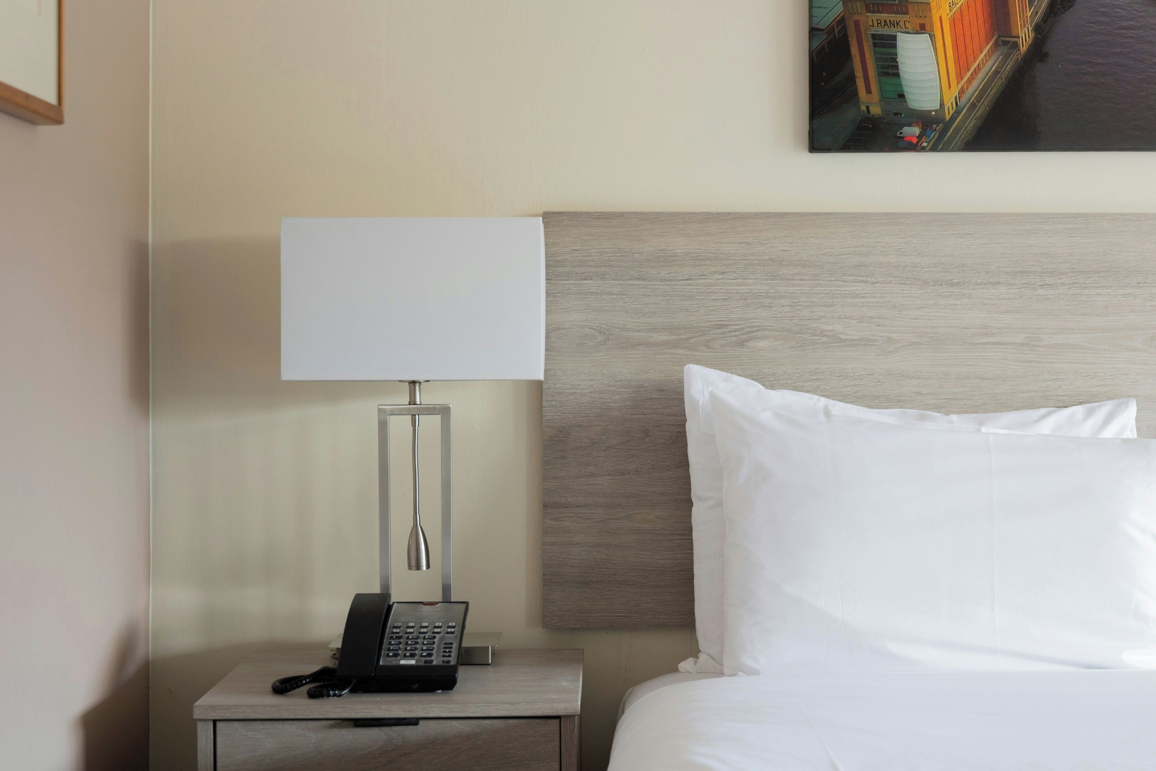 Habitación de hotel con cama, mesita de noche con lámpara y teléfono.
