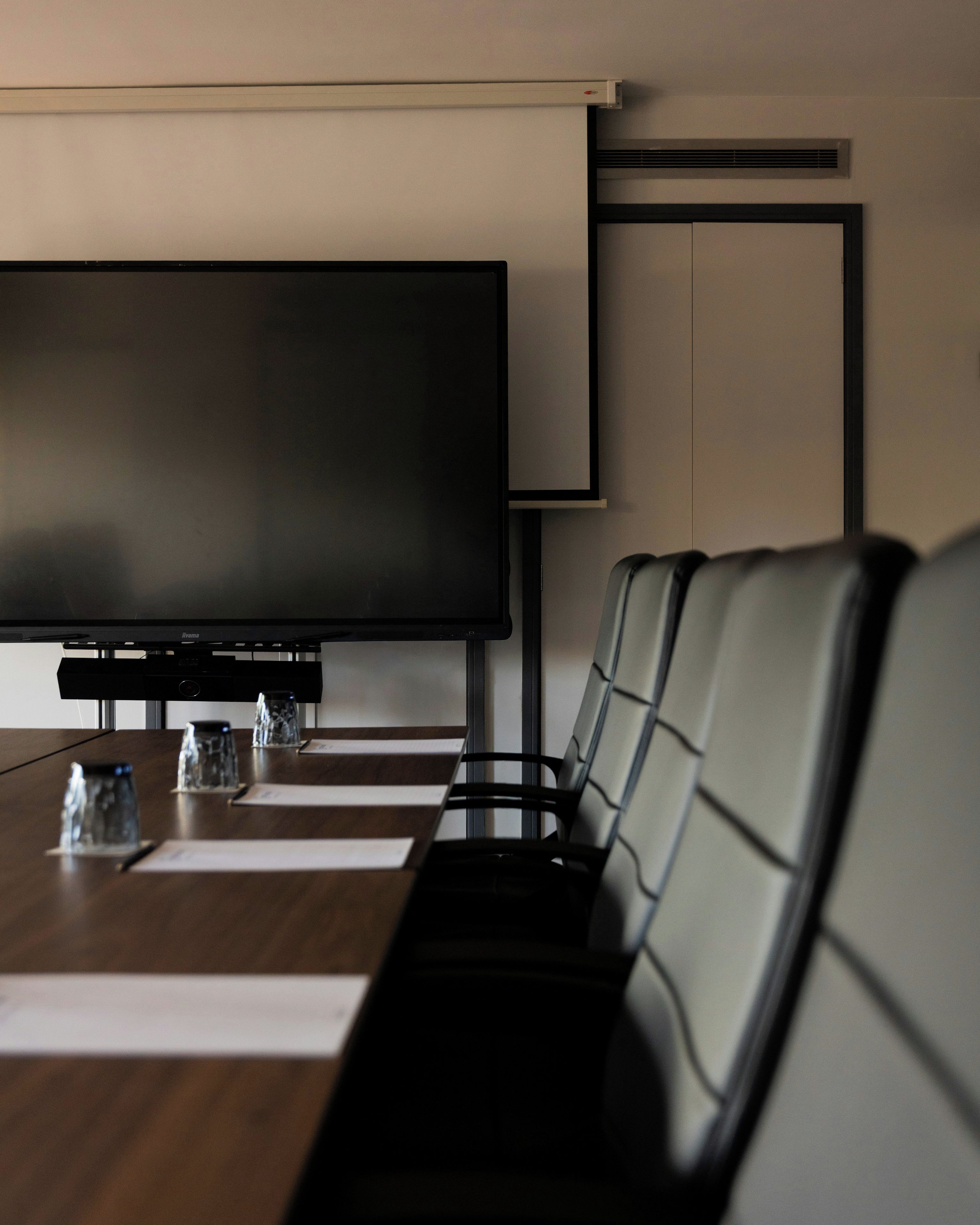 Une salle de conférence équipée d’un grand téléviseur à écran plat, d’une longue table et de plusieurs fauteuils en cuir.