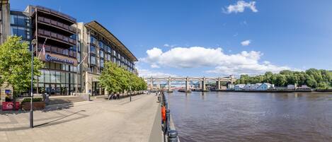 A waterfront hotel with a modern design, featuring a glass facade and a prominent entrance.
