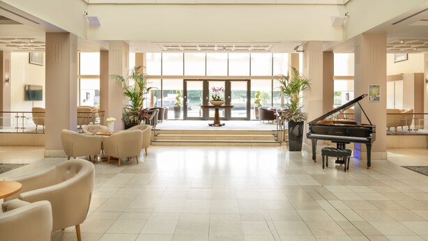 A spacious lobby with a grand piano, comfortable seating, and large windows offering a view of the outdoors. - Copthorne Hotel Newcastle (Newcastle-upon-Tyne)