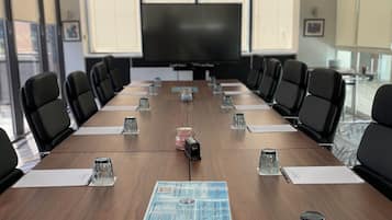A conference room with a long table, black chairs, a large screen, and a projector.
