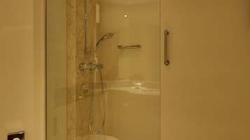 A modern bathroom with a glass-enclosed shower, a marble-tiled floor, and a white sink.