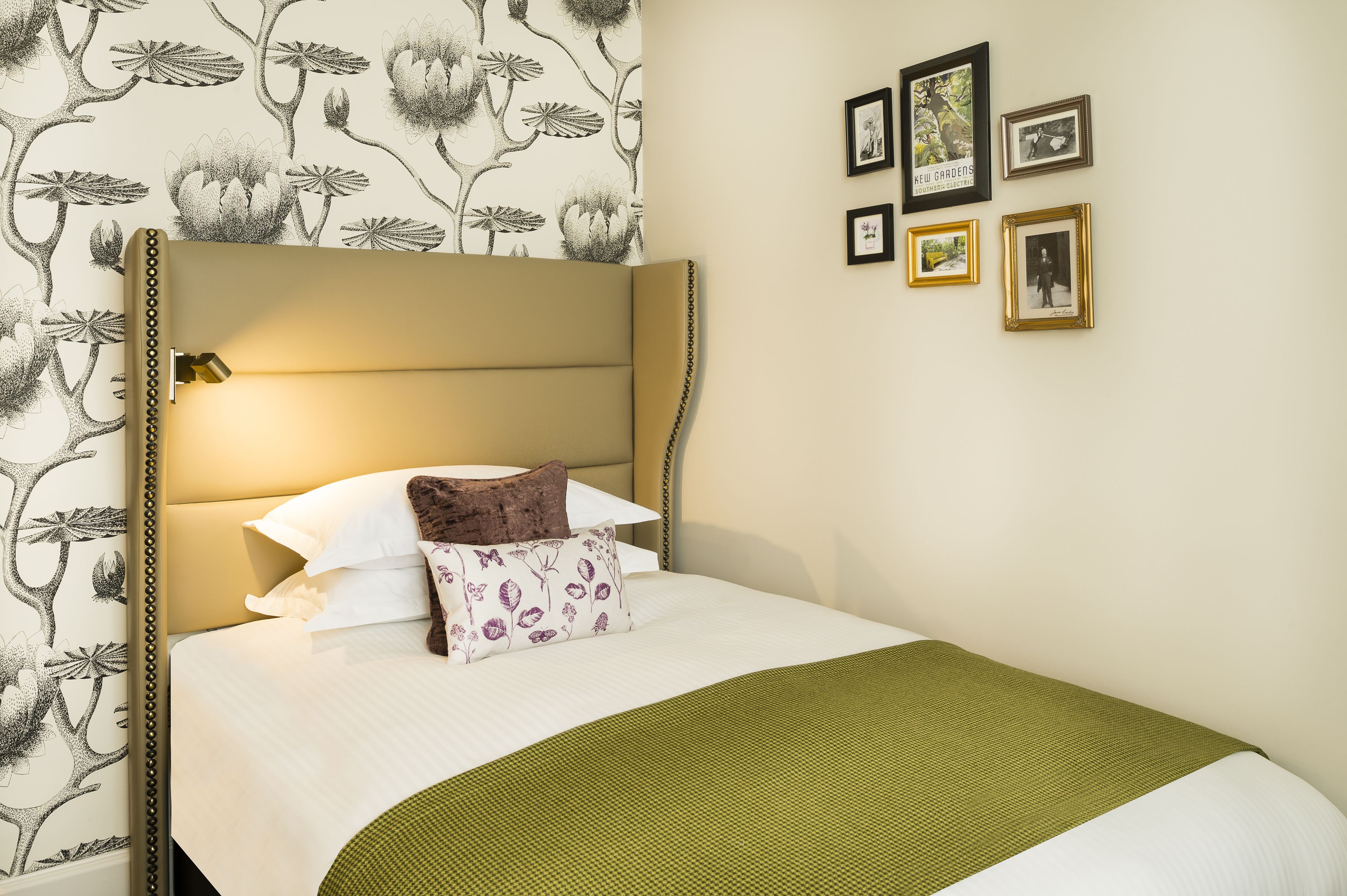 A neatly made bed with a headboard, white bedding, and a green throw blanket.
