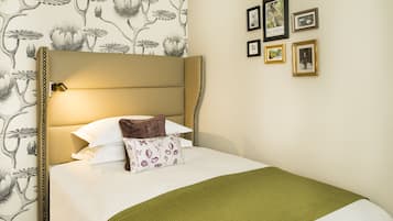 Cama bem arrumada com cabeceira, roupa de cama branca e manta verde.