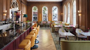 A bar area with a long counter, multiple bar stools, and a variety of bottles and glasses. - The Bailey's Hotel London Kensington (London)