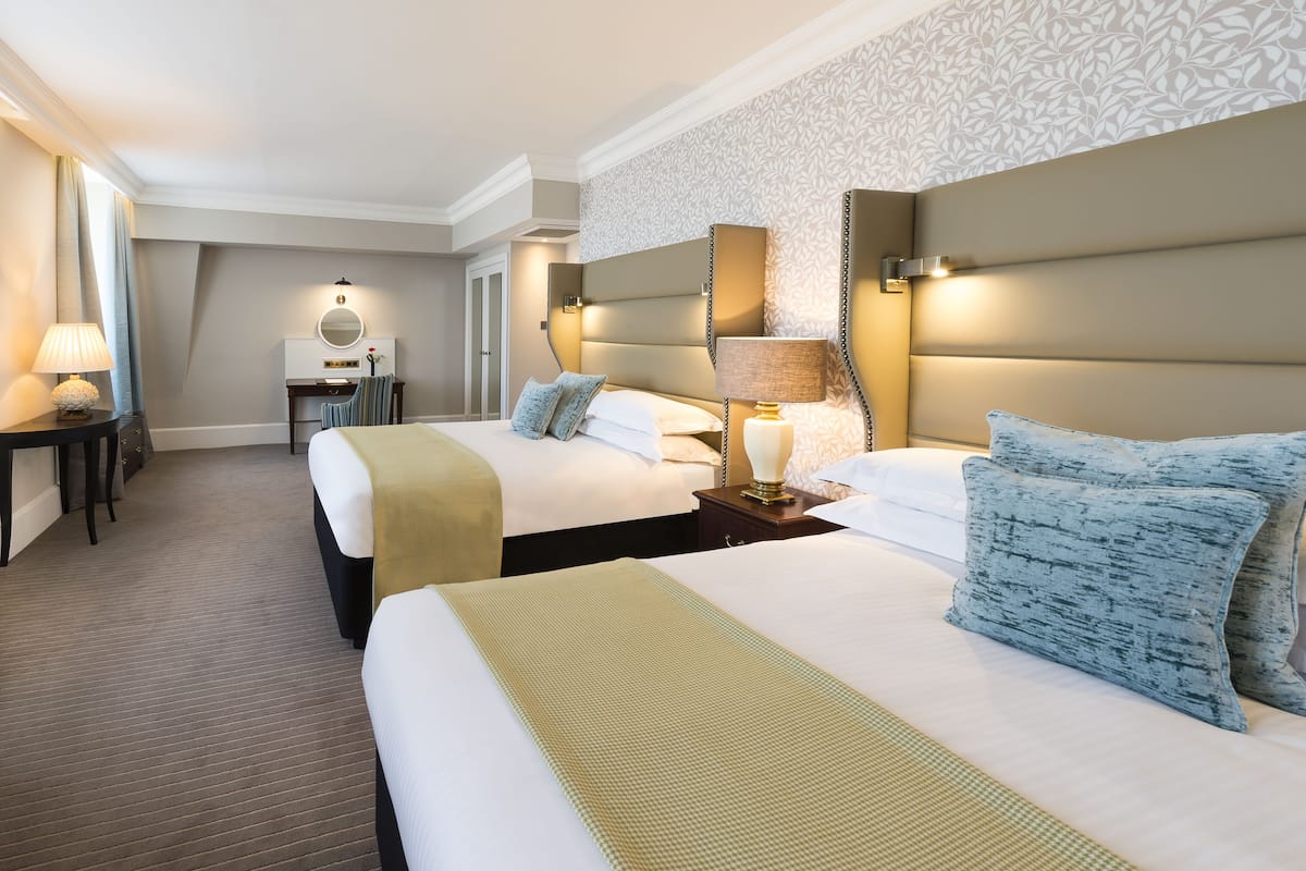 Habitación de hotel con dos camas, un escritorio y un espejo.