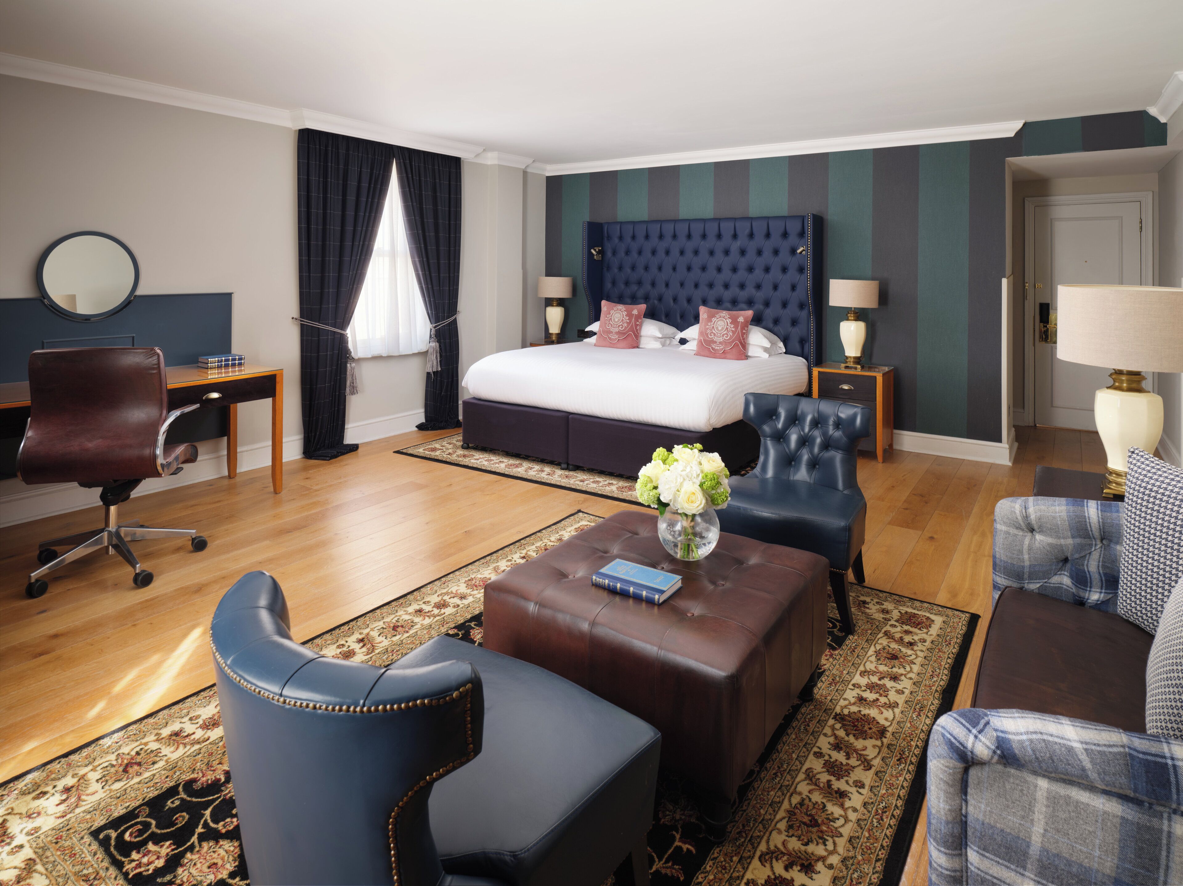Ein Hotelzimmer mit einem großen Bett, einem Schreibtisch, einem Sessel, einem Couchtisch und einer Couch.