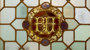 Una ventana de vitral con un diseño geométrico y un emblema central.