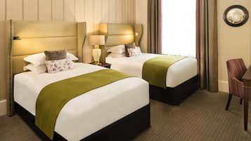 Habitación de hotel con dos camas, un espejo, una silla y una lámpara.