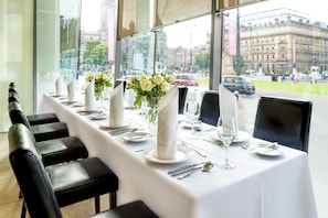 A restaurant with a long table set for a meal, chairs, and a view of the city through large windows. - Millennium Hotel Glasgow (Glasgow)