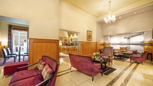 A spacious lobby with plush seating, a chandelier, and a view of the bar area.