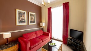 A red sofa, a TV, a coffee table, and two framed pictures on the wall.