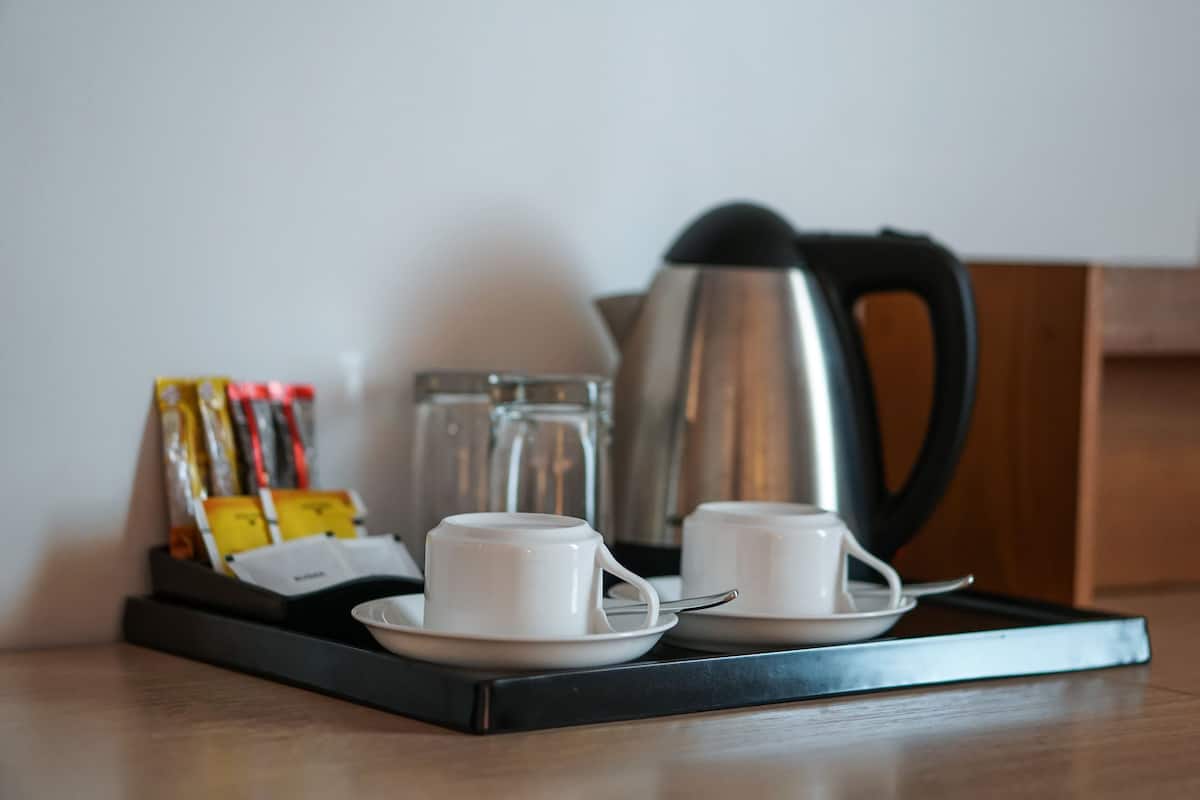 A tray with two white cups and saucers, a glass carafe, and a coffee pot on a wooden table.