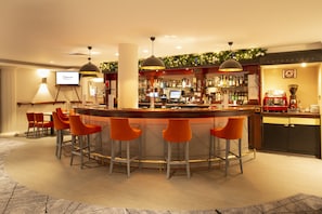 A bar area with a circular bar, orange bar stools, and a television screen displaying 'Caphorne'. - Copthorne Hotel Aberdeen (Aberdeen)