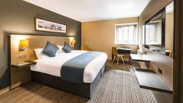 A hotel room with a large bed, bedside tables, a desk, and a chair.