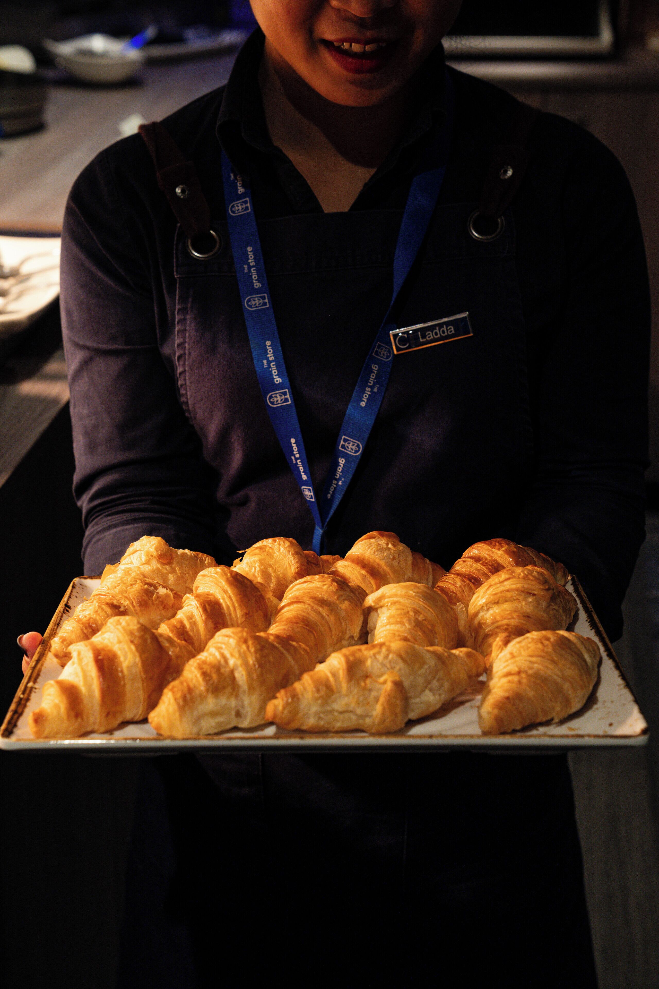 Eine Person hält eine Platte mit Croissants.