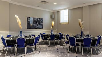 A conference room with round tables, blue chairs, and decorative pampas grass.