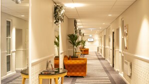 A hotel corridor with a checkered carpet, orange armchairs, and a table with a magazine. - Copthorne Hotel Aberdeen (Aberdeen)