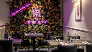 A restaurant interior with a floral wall backdrop, a neon sign reading "THE grain store", and a framed picture on the wall. - Copthorne Hotel Aberdeen (Aberdeen)