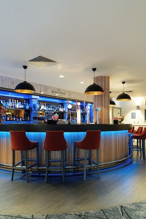 Zona de bar con mostrador, taburetes y un letrero que dice 'The Grain Store'.
