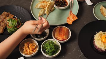A table set with various dishes, including dumplings, kimchi, and a dish with shredded meat and an egg.