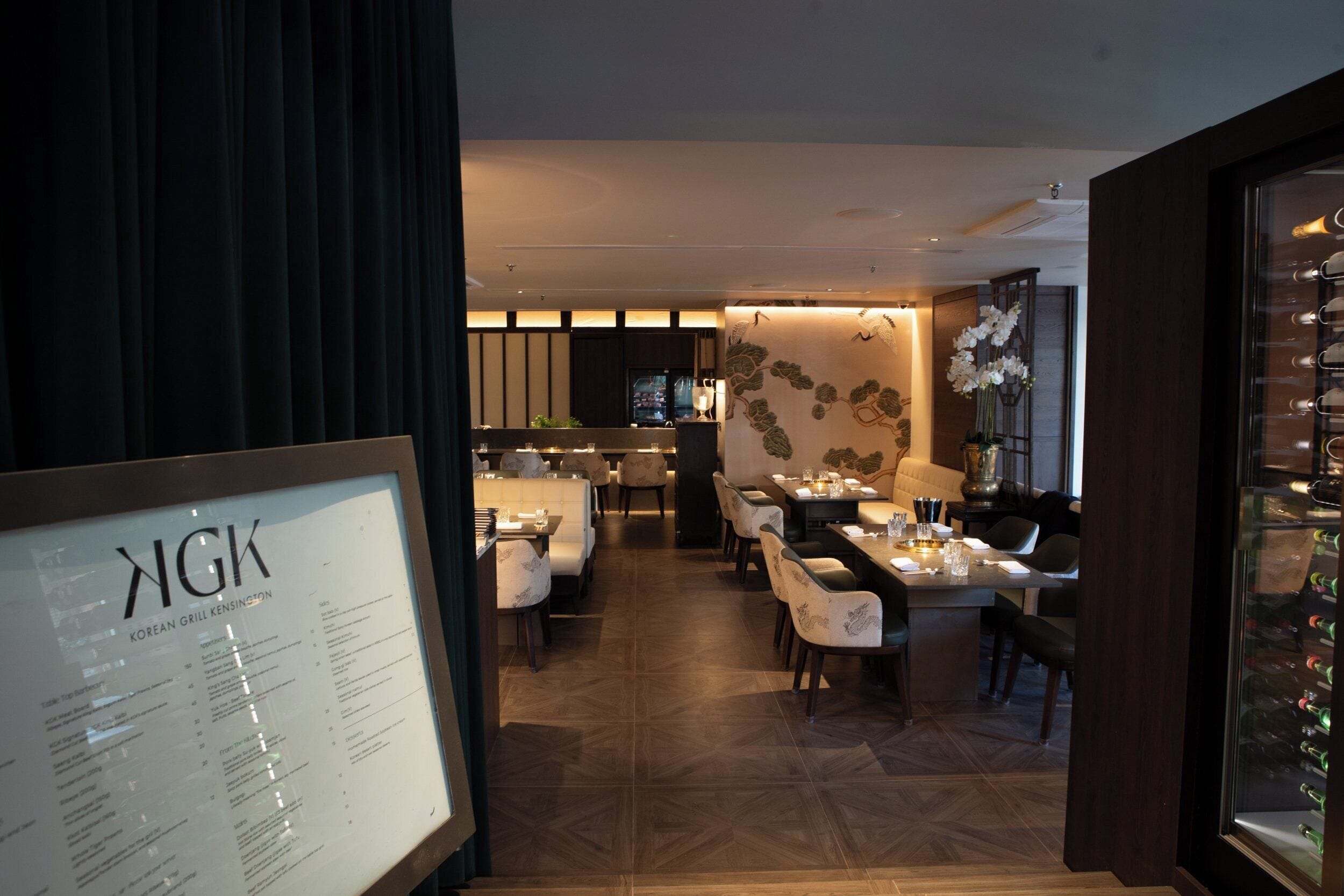 Un restaurant doté d’un tableau affichant le menu, d’un plancher en bois et de différents types de sièges.
