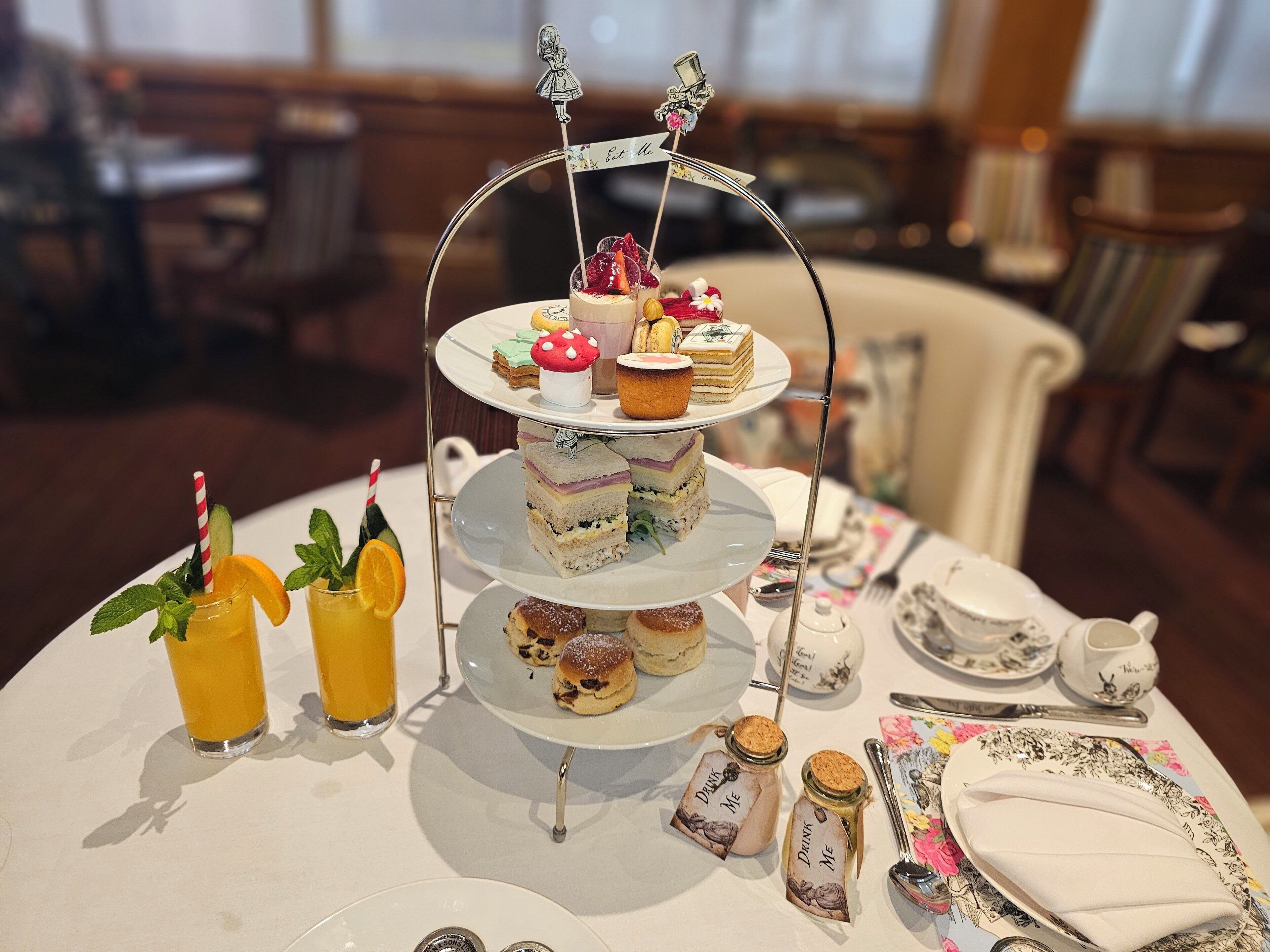 Un soporte de tres niveles para postres con varios pasteles y una pequeña bandera que dice 