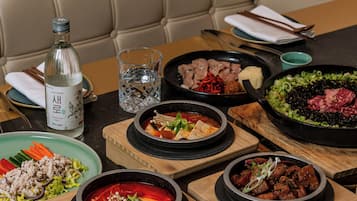 A table set with various Korean dishes, a bottle of liquor, and a glass of water.